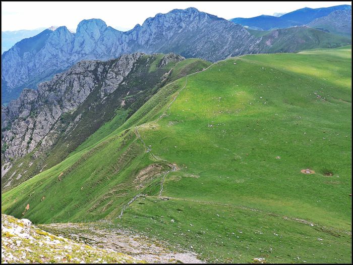 La suavidad del terreno de la veiga Candioches se ve alterada por la verticalidad de la vertiente norteña. Al fondo la peñas de La Mesa
